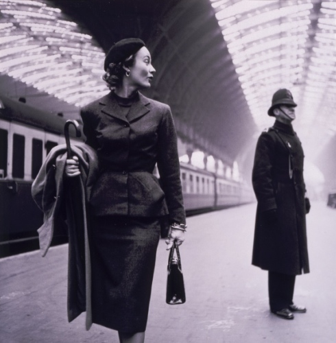 A model at Victoria Station in London. The pencil skirt, wrist-length gloves, and beret were typical signs of fragility in 1950s fashion.